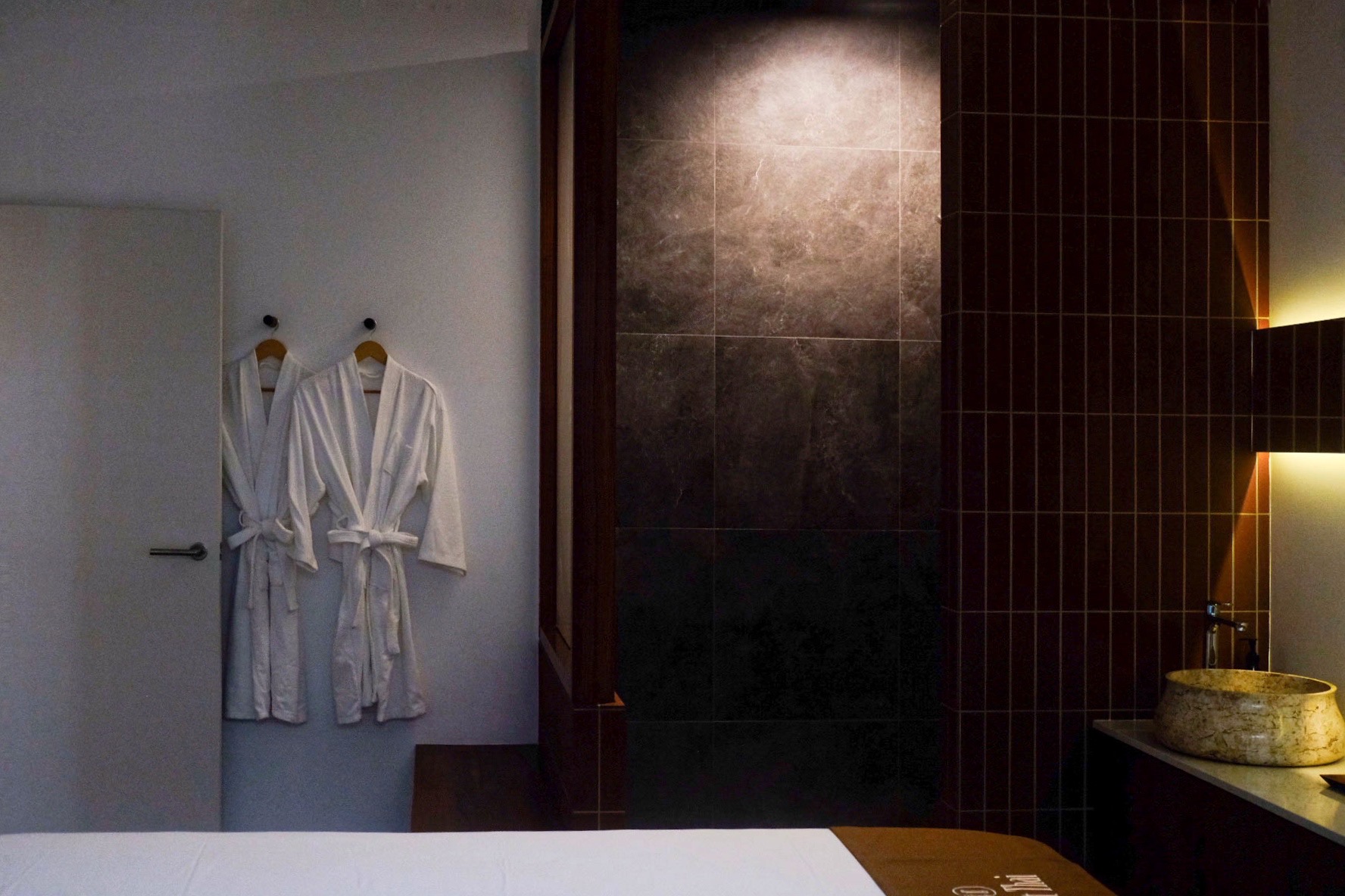 Loft Thai Spa & Wellness treatment room with robes and stone basin