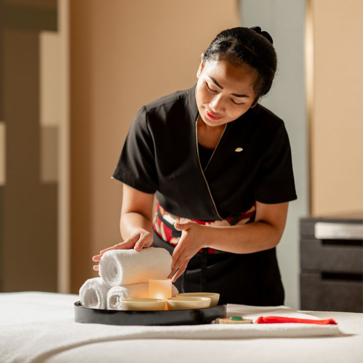 Spa therapist preparing towels and amenities in a treatment room